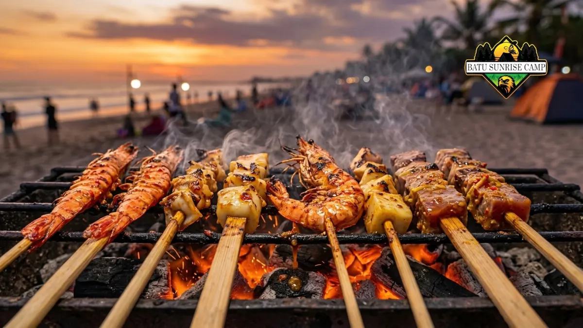 Tusuk sate seafood campur berisi udang, cumi, dan potongan ikan dengan bumbu kecap bawang putih dipanggang di atas bara arang saat camping pantai