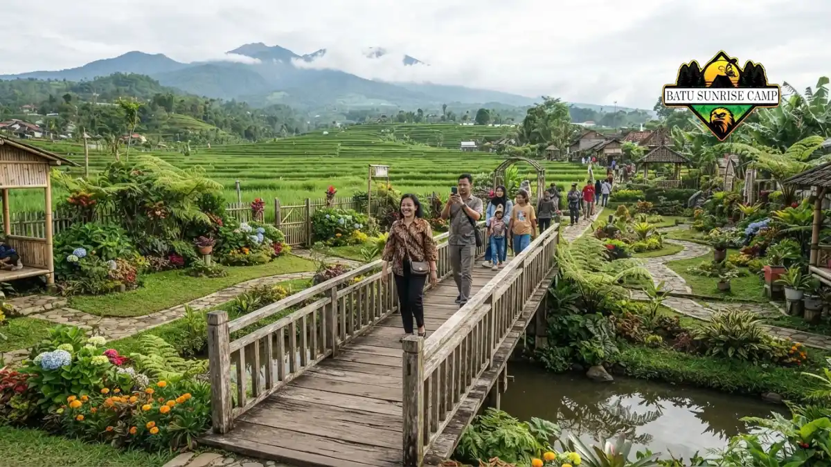 Taman bunga dan papan nama di area Desa Wisata Pujon Kidul dengan latar pegunungan hijau